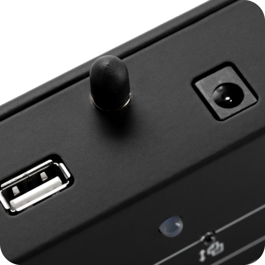 Close-up of a black electronic device with USB port and control knob on a white background