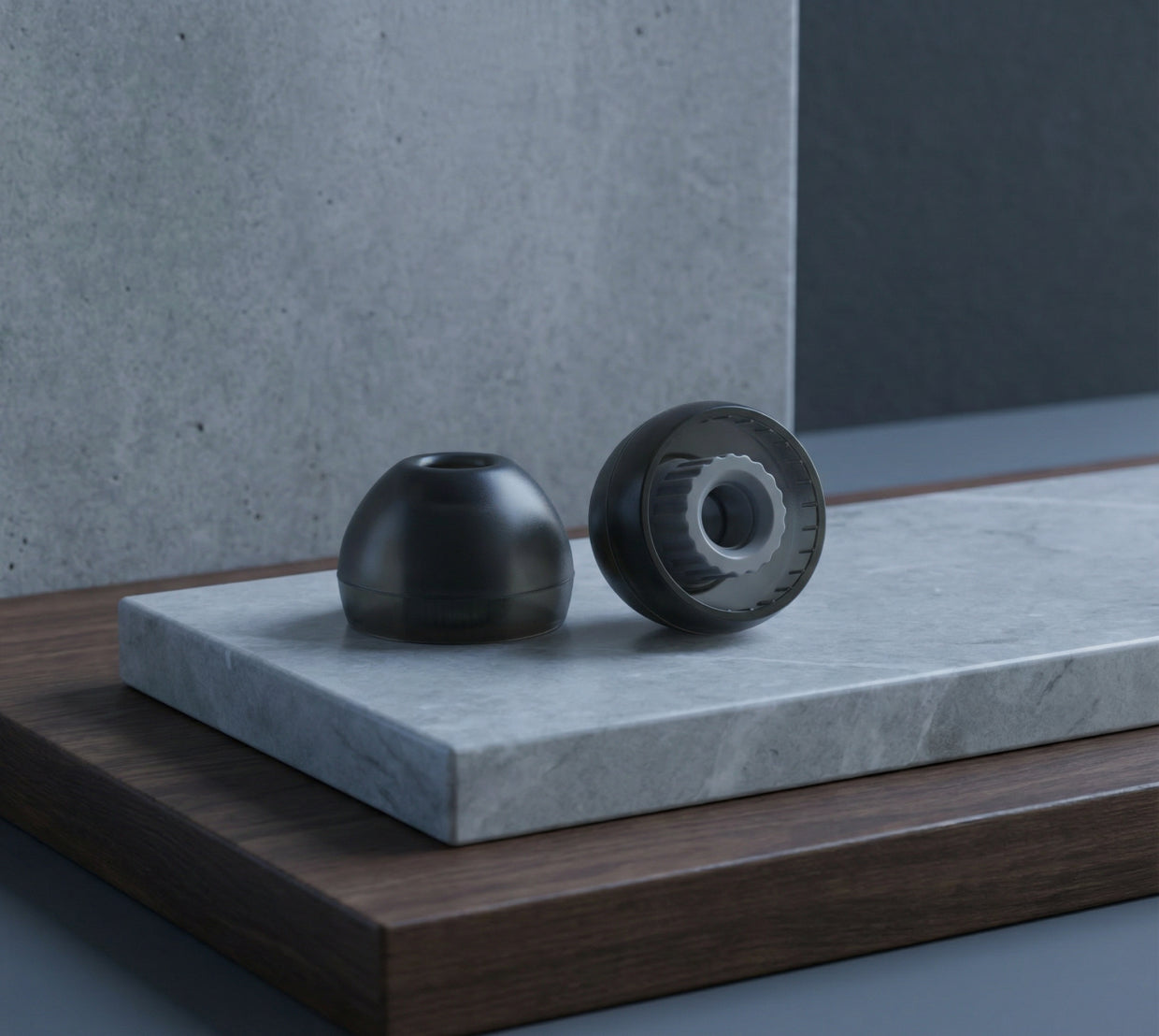 Two black ear tips displayed on stacked stone and wood platforms