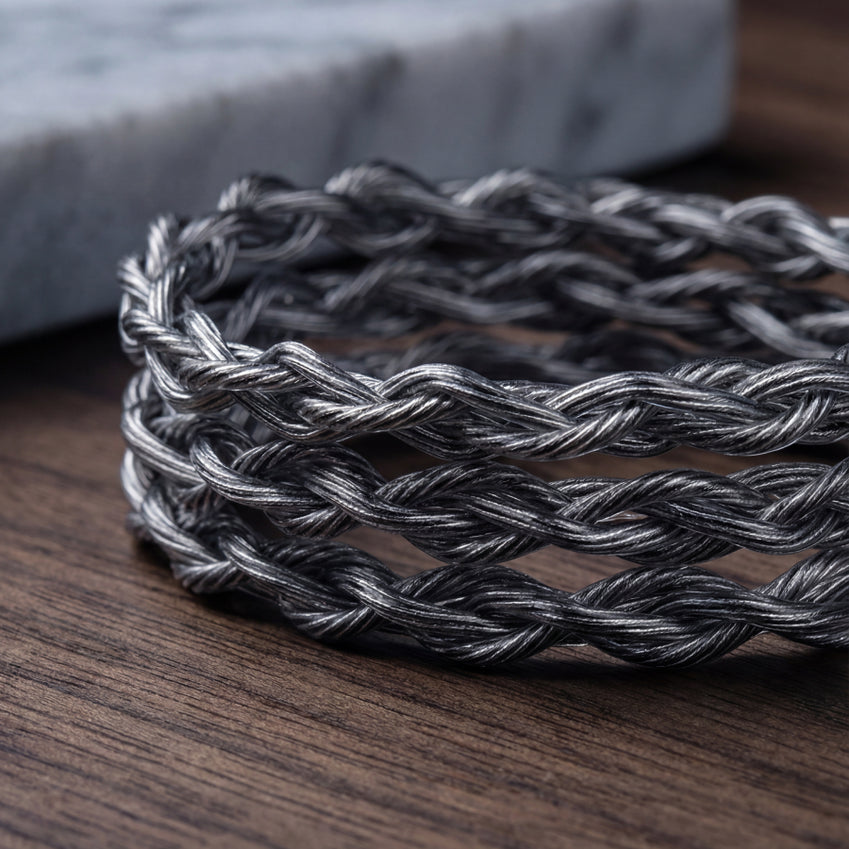Close-up of a braided silver and black audio cable on a wooden surface