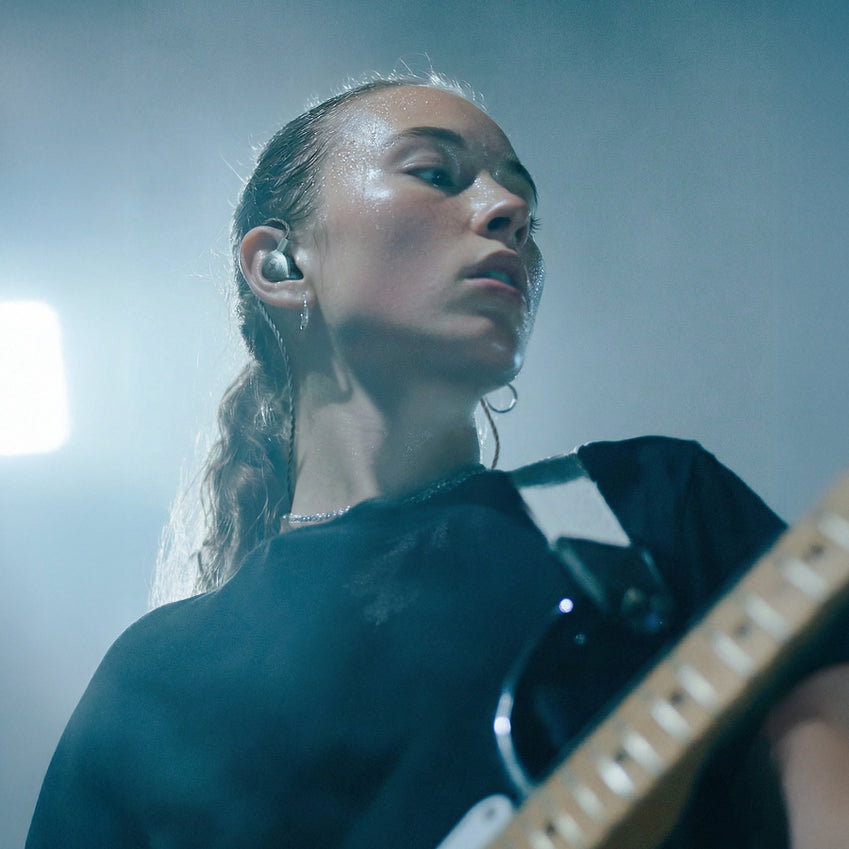 Guitarist wearing an in-ear monitor with an electric guitar