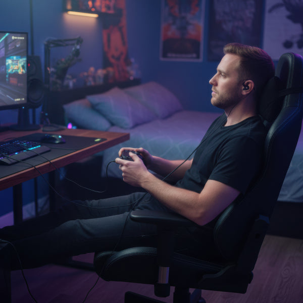 Person wearing wired earbuds while gaming at a computer