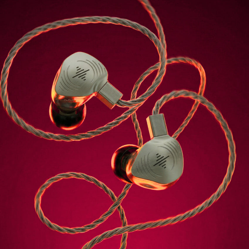 Pair of silver wired in-ear monitors with braided cable on a red background