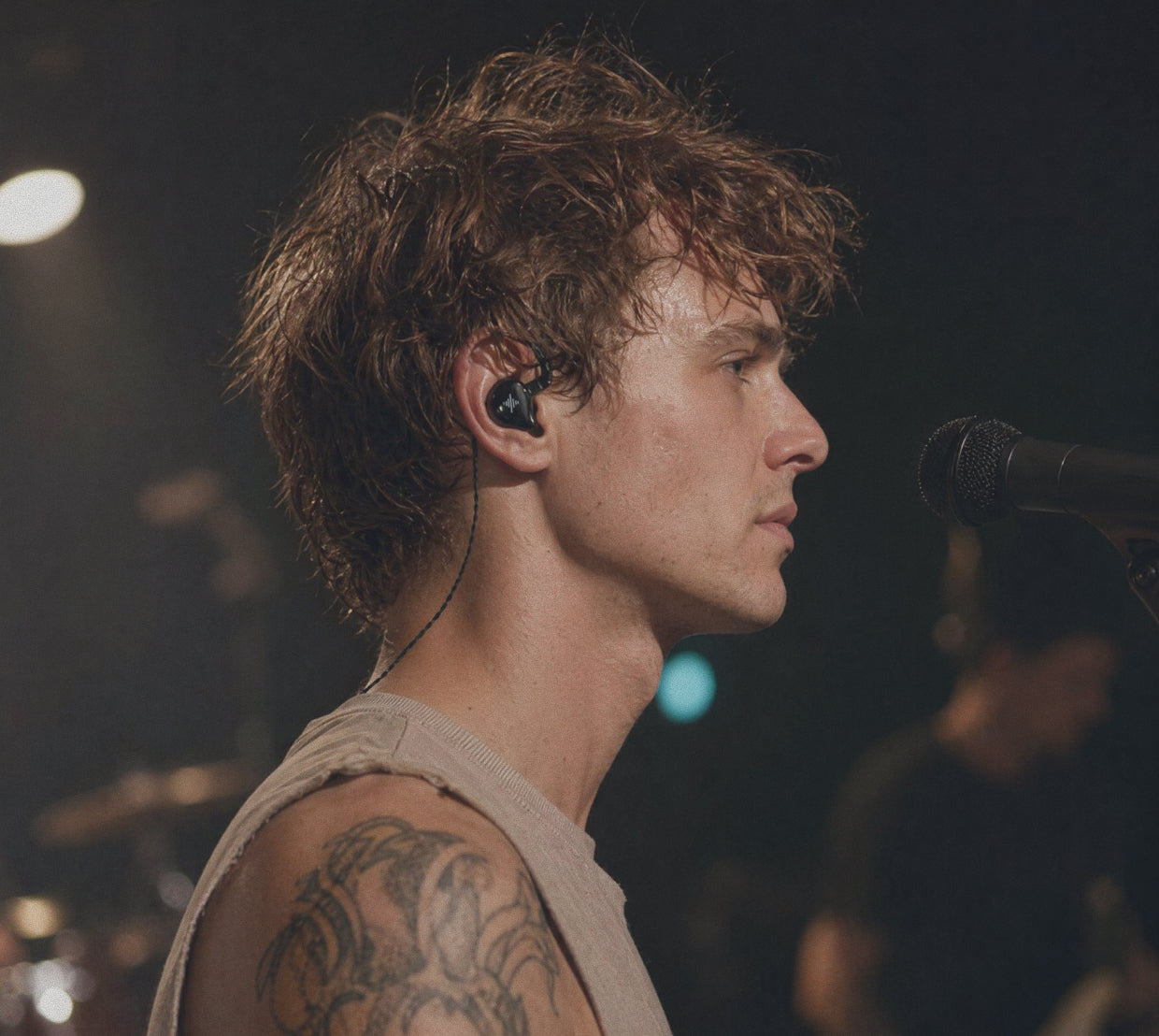 Performer wearing a black Wave in-ear monitor near a microphone