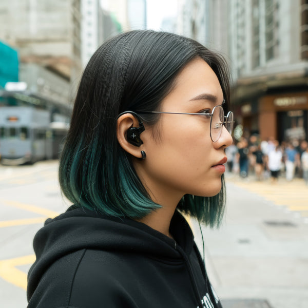 Woman wearing a black wireless earbud and glasses outdoors
