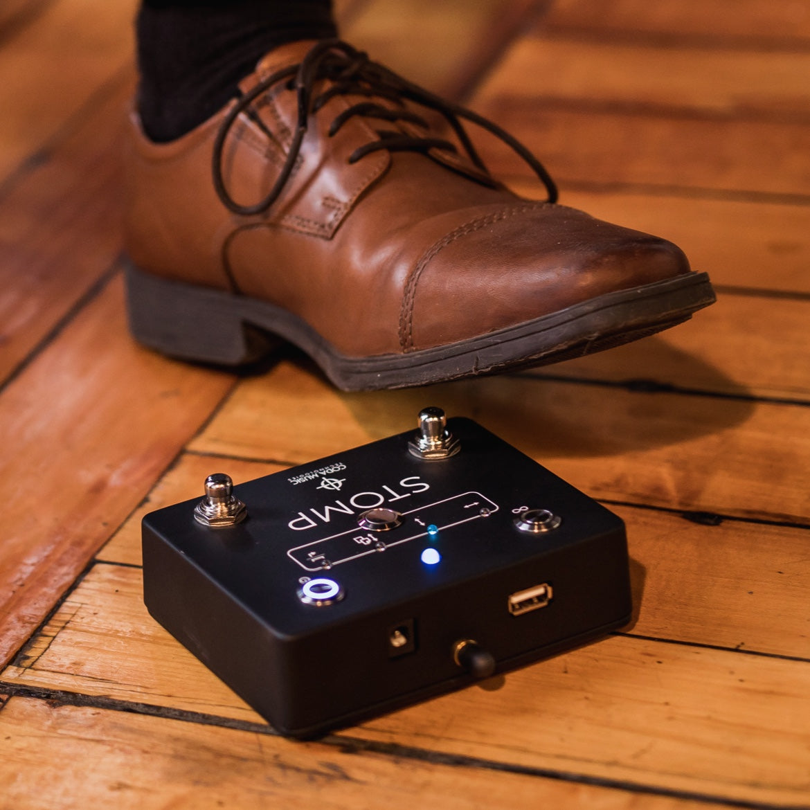 黑色 Soundbrenner Stomp 脚踏板上方的一只棕色鞋子